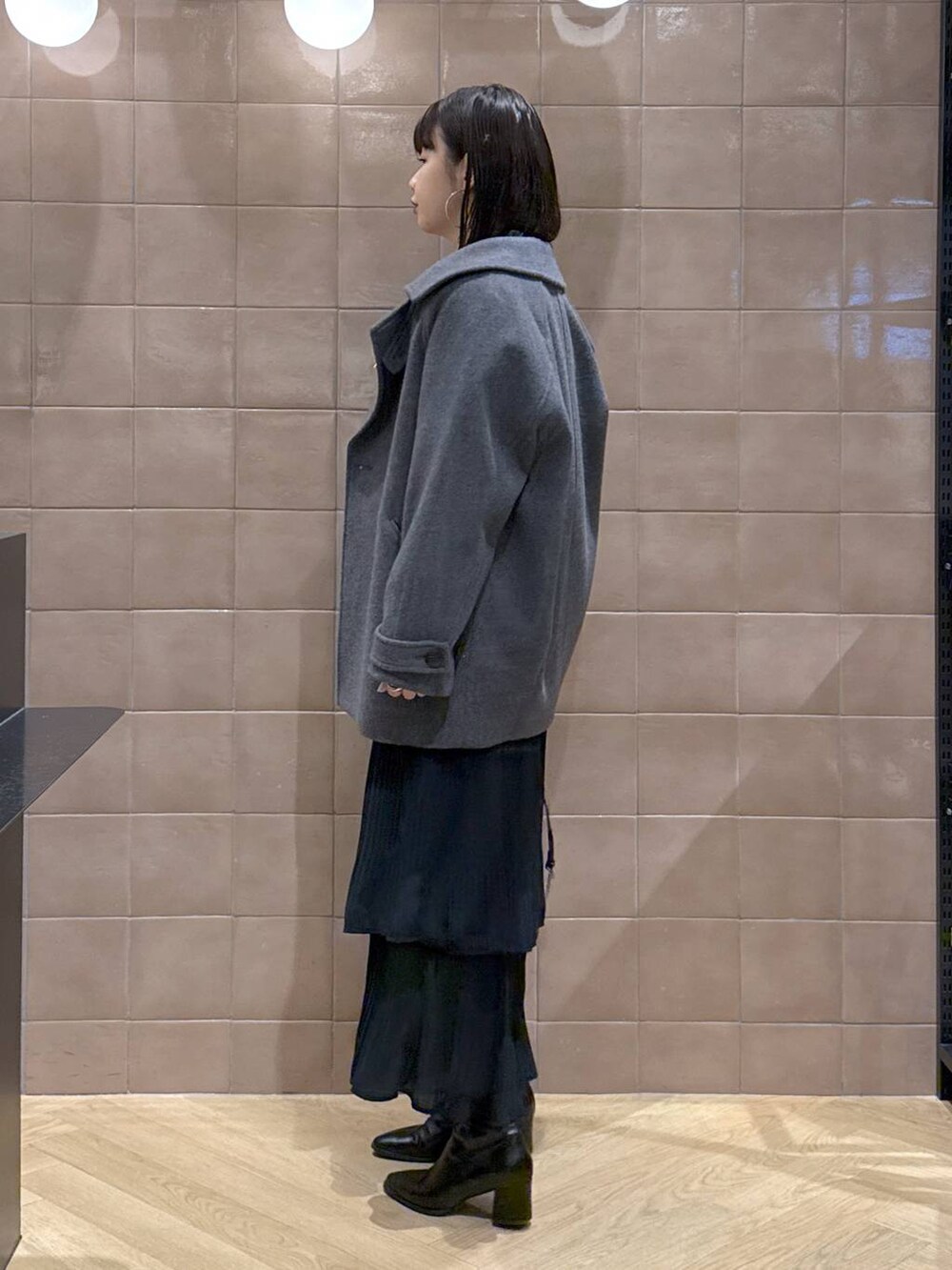 グレー系のピーコート、ホワイト系のTシャツ/カットソー、ブラック系のスカートを着用したレディースの冬コーディネートの4枚目の写真