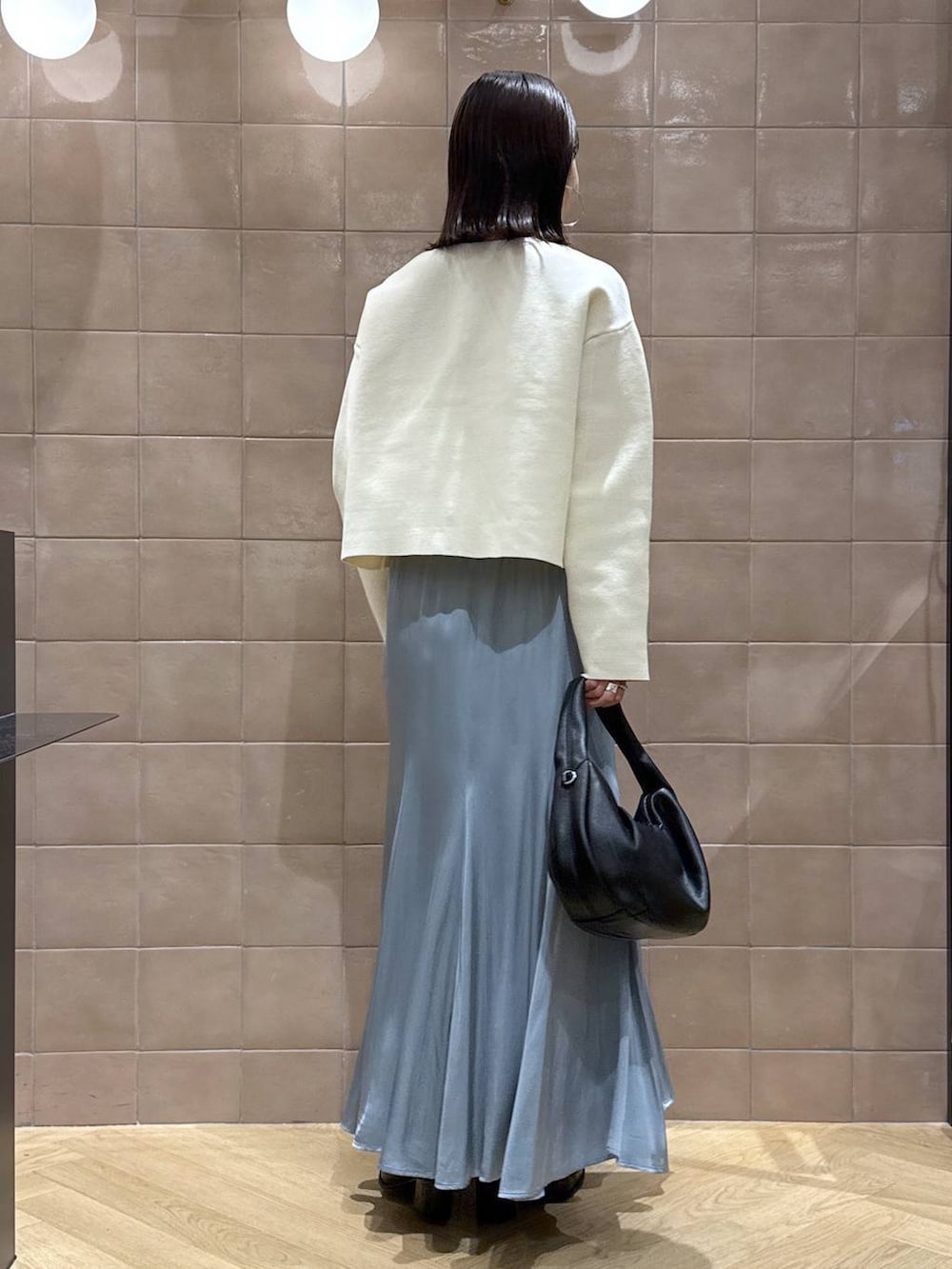 ブラック系のハンドバッグ、ホワイト系のカーディガン/ボレロ、ブルー系のスカートを着用したレディースの秋コーディネートの3枚目の写真