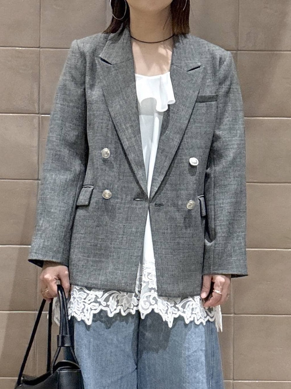 ブルー系のデニムパンツ、ブラック系のテーラードジャケット、ホワイト系のキャミソールを着用したレディースの春コーディネートの5枚目の写真