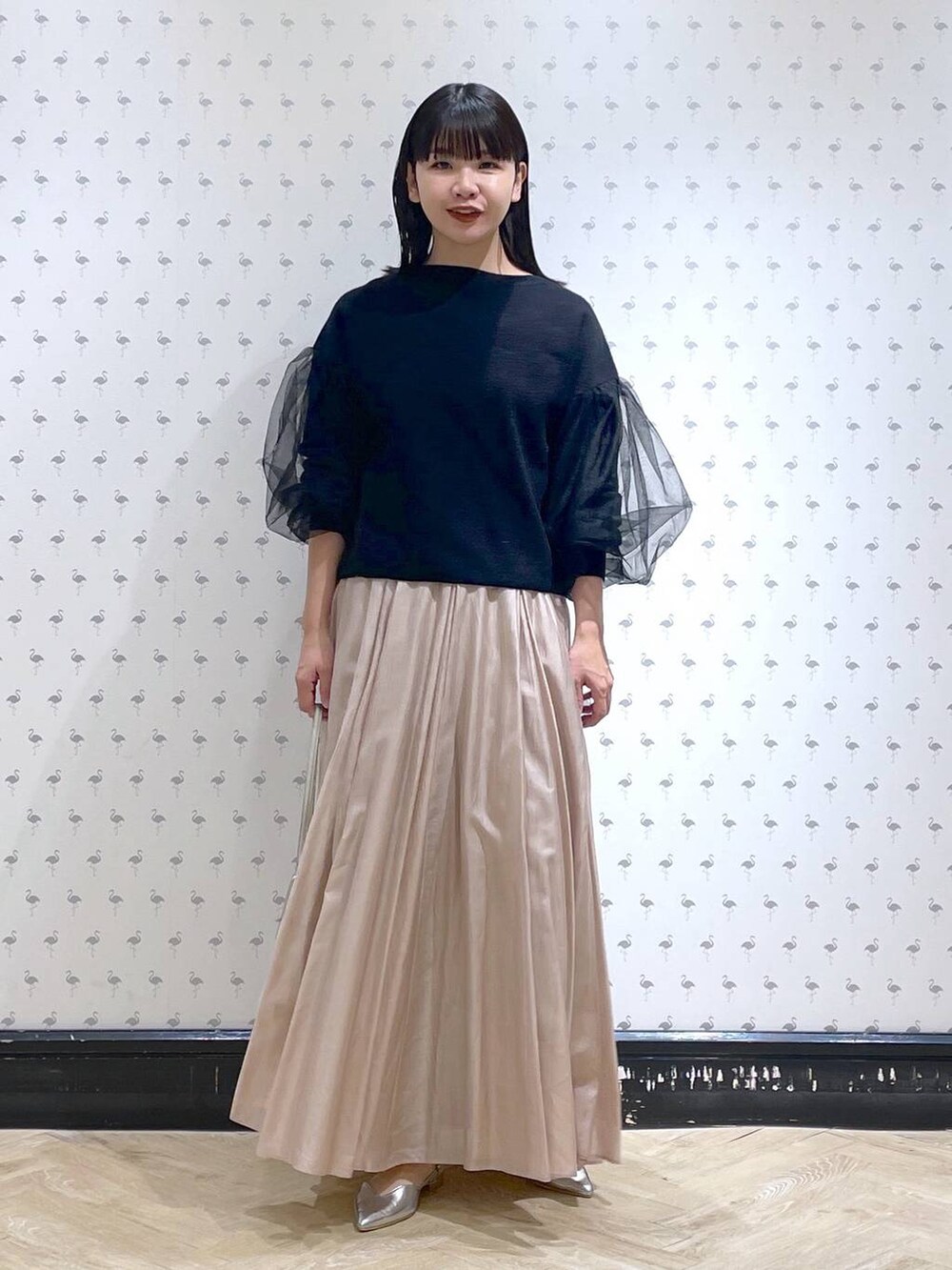 シルバー系のショルダーバッグ、ベージュ系のスカート、シルバー系のパンプスを着用したレディースの冬コーディネートの2枚目の写真