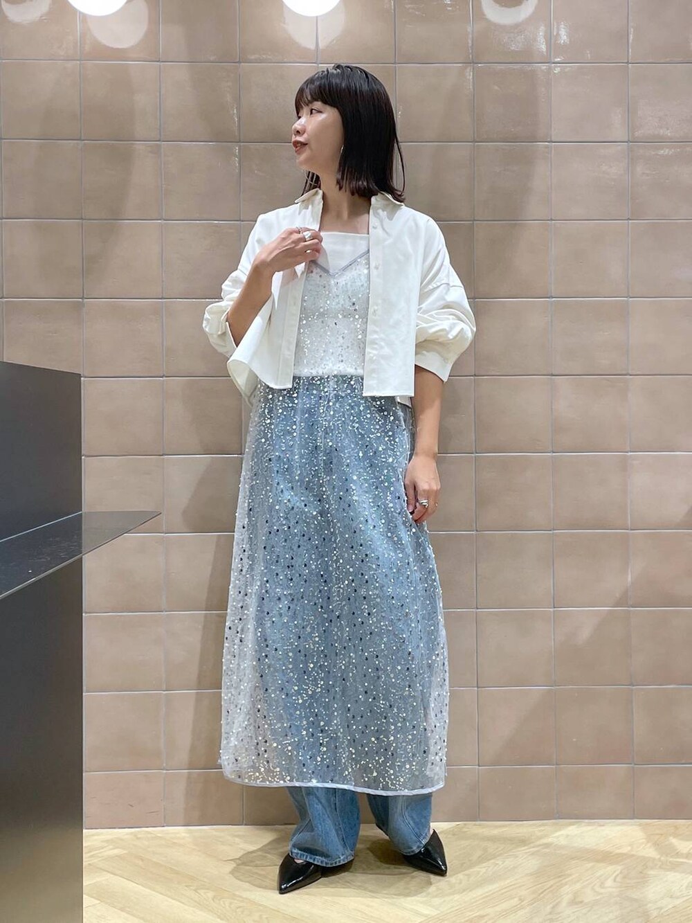 ブルー系のデニムパンツ、ブラック系のパンプス、グレー系のワンピースを着用したレディースの秋コーディネートの2枚目の写真