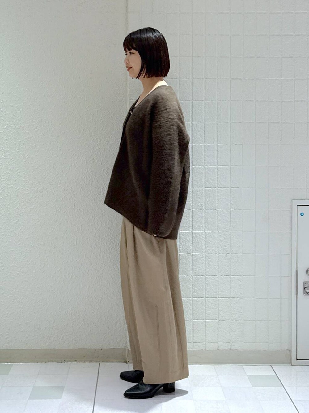 ブラウン系のカーディガン/ボレロ、ベージュ系のスラックス、ブラック系のブーツを着用したレディースの秋コーディネートの5枚目の写真