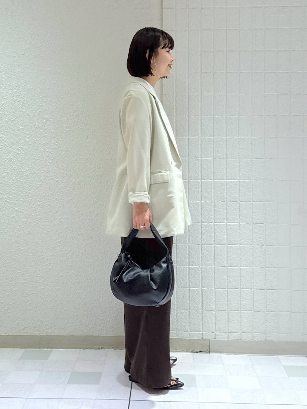 ブラック系のハンドバッグ、ブラック系のサンダル、ベージュ系のテーラードジャケットを着用したレディースの春コーディネートの3枚目の写真