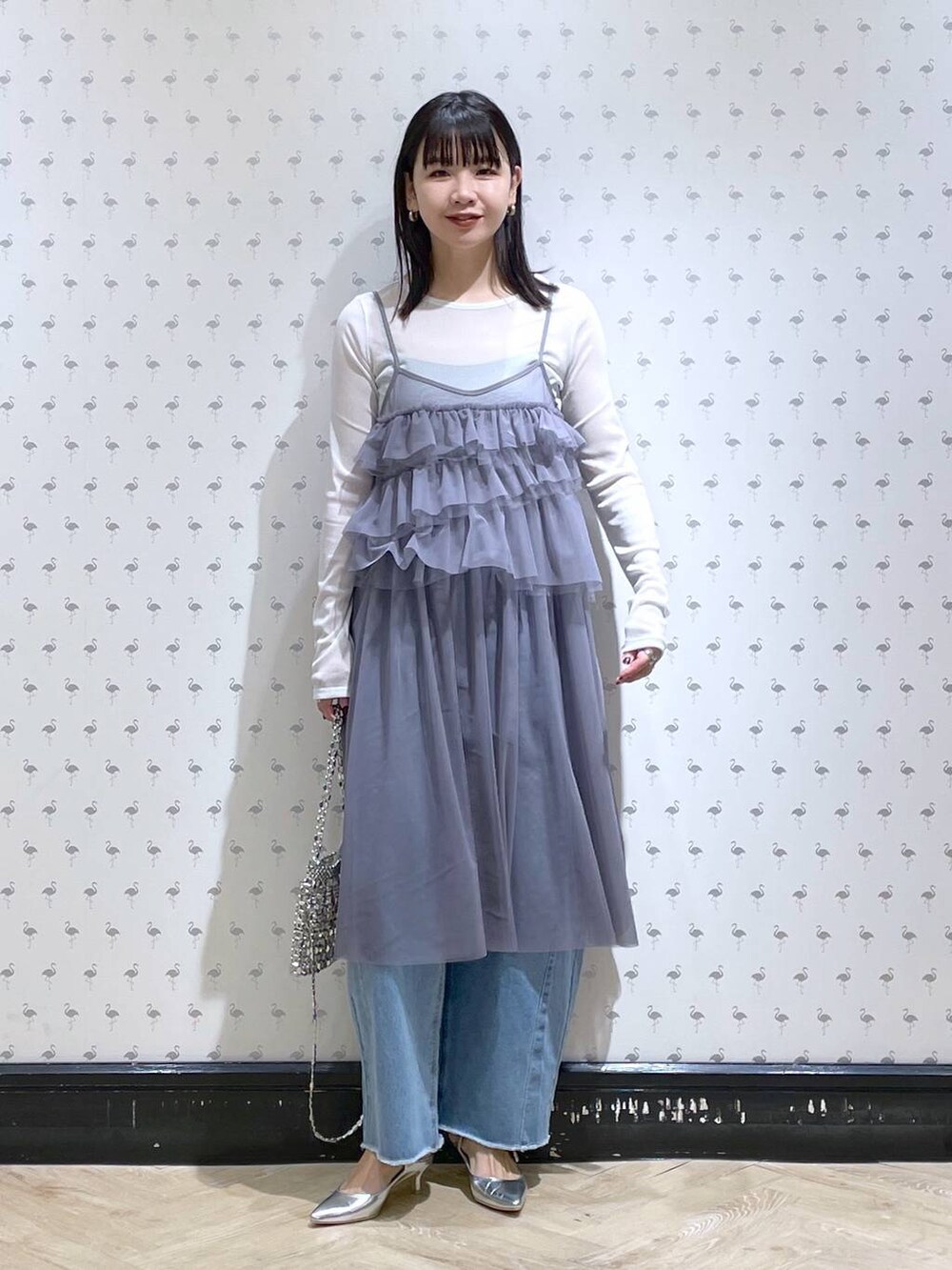 シルバー系のサンダル、ブルー系のデニムパンツ、シルバー系のショルダーバッグを着用したレディースの冬コーディネートの2枚目の写真