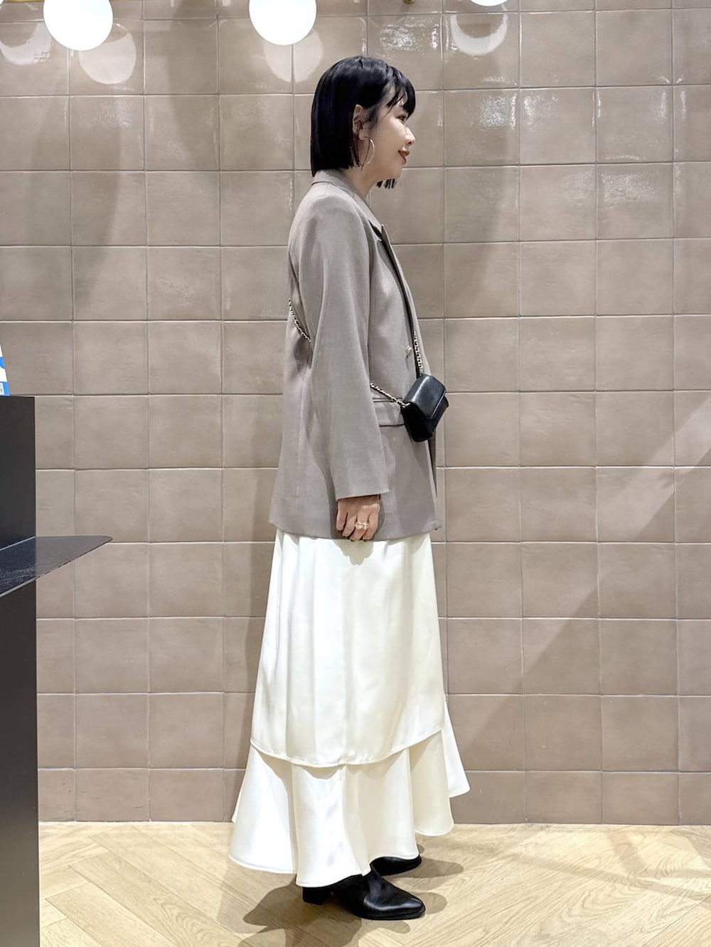 ブラック系のブーツ、グレー系のテーラードジャケット、ホワイト系のワンピースを着用したレディースの秋コーディネートの3枚目の写真