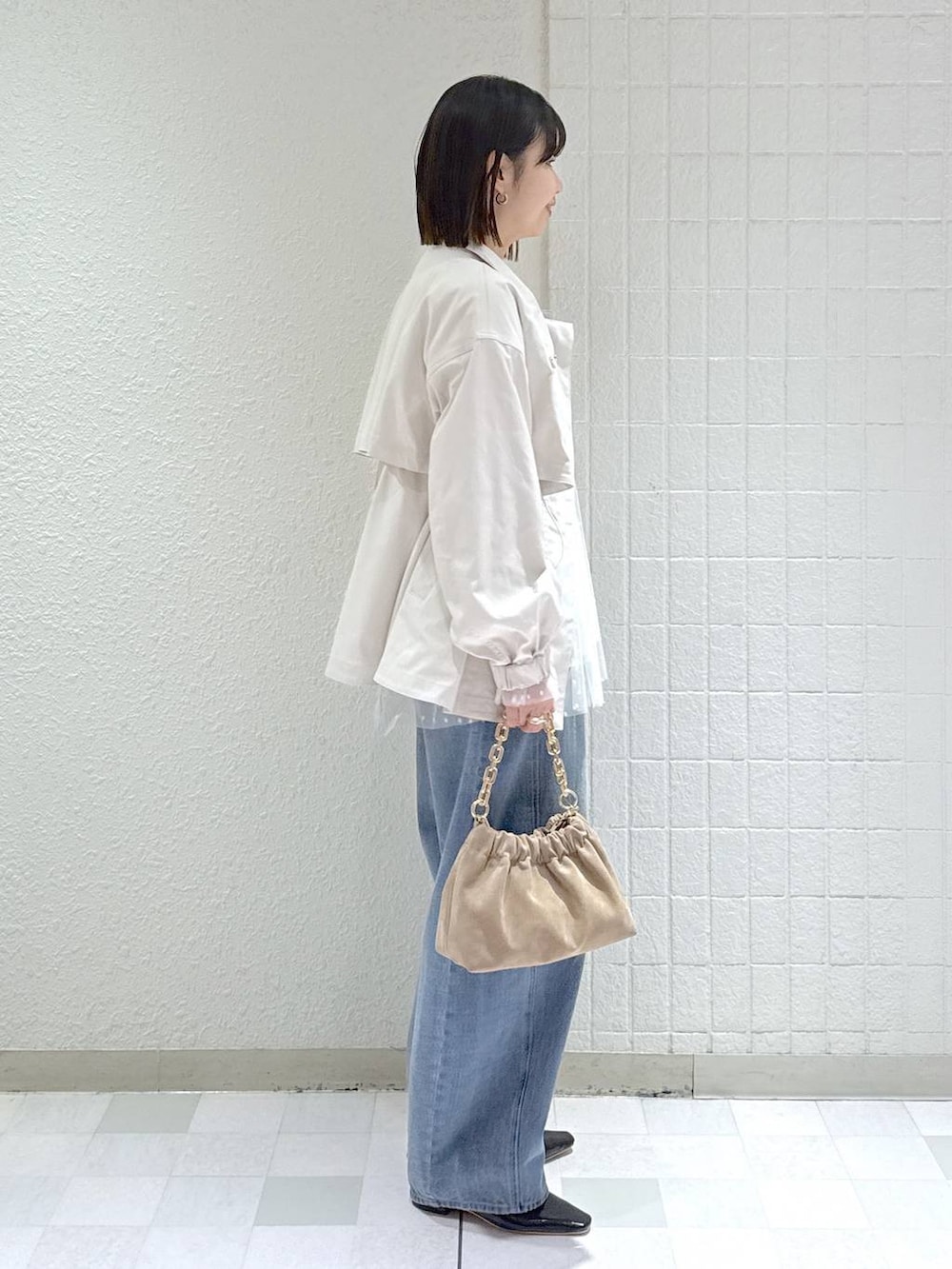 ブルー系のデニムパンツ、ベージュ系のブルゾン、ベージュ系のショルダーバッグを着用したレディースの春コーディネートの2枚目の写真