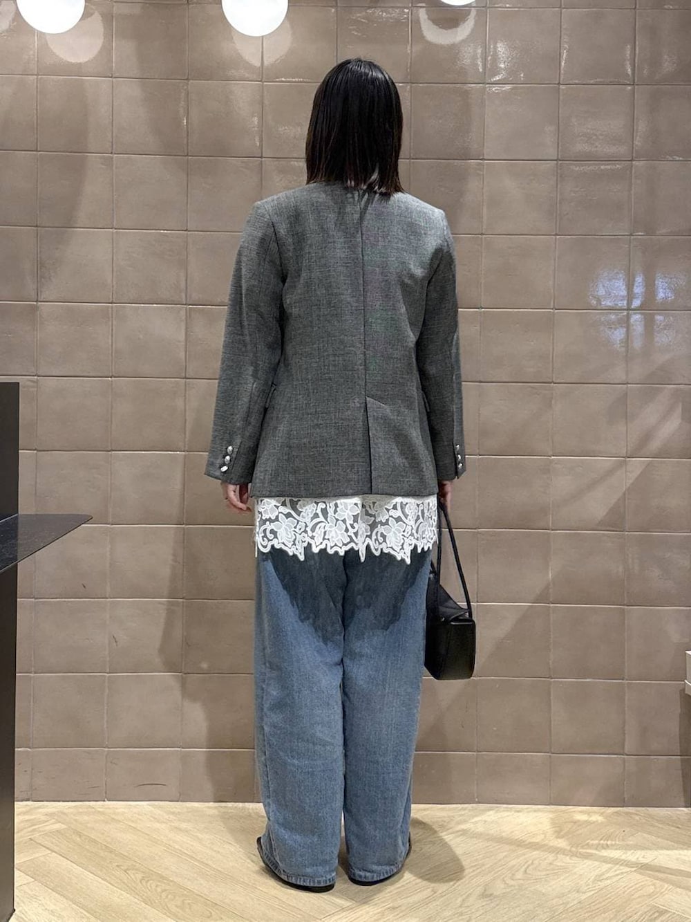 ブルー系のデニムパンツ、ブラック系のテーラードジャケット、ホワイト系のキャミソールを着用したレディースの春コーディネートの3枚目の写真