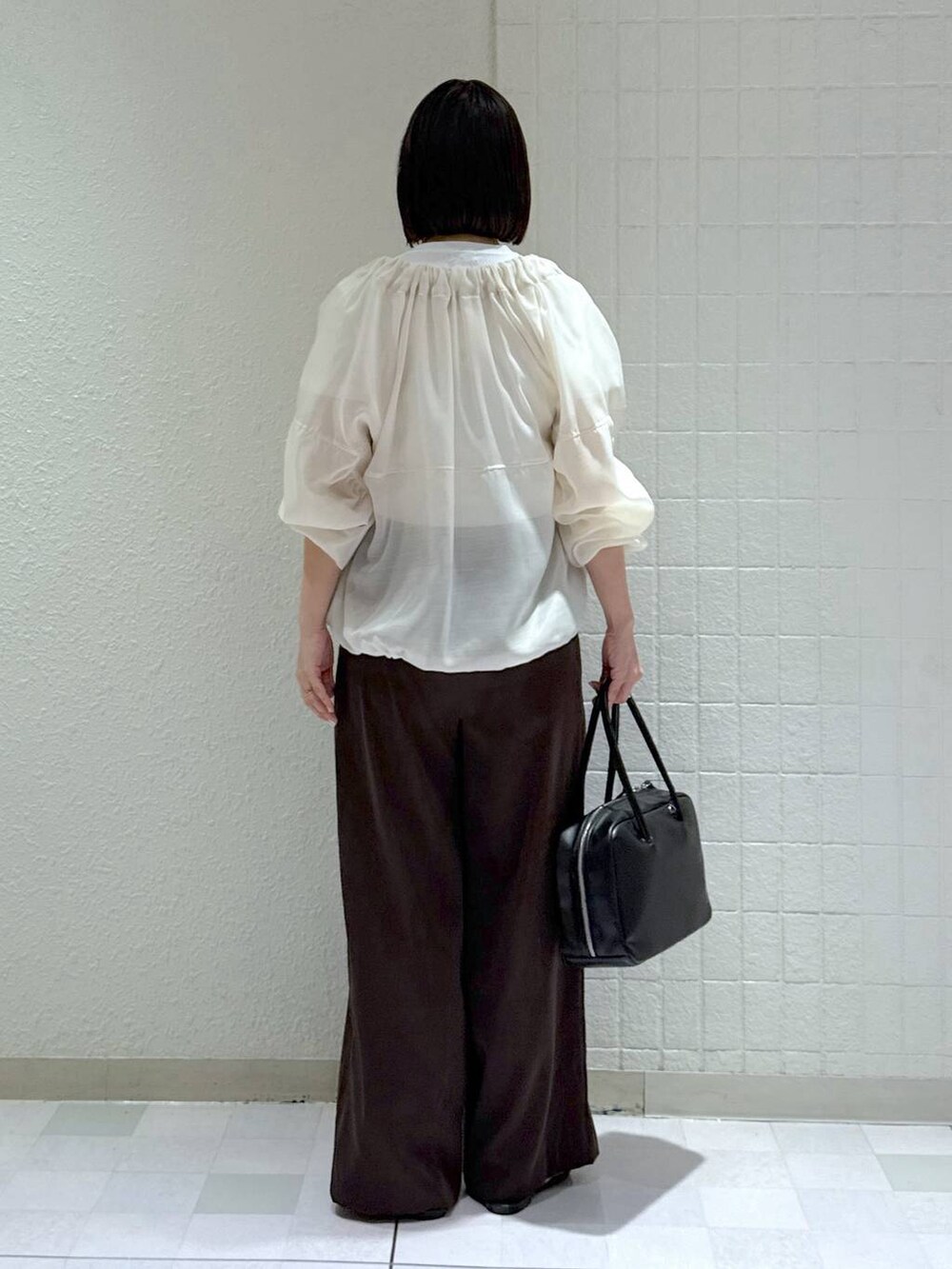 ブラック系のボストンバッグ、ホワイト系のブルゾン、ブラック系のサンダルを着用したレディースの春コーディネートの4枚目の写真