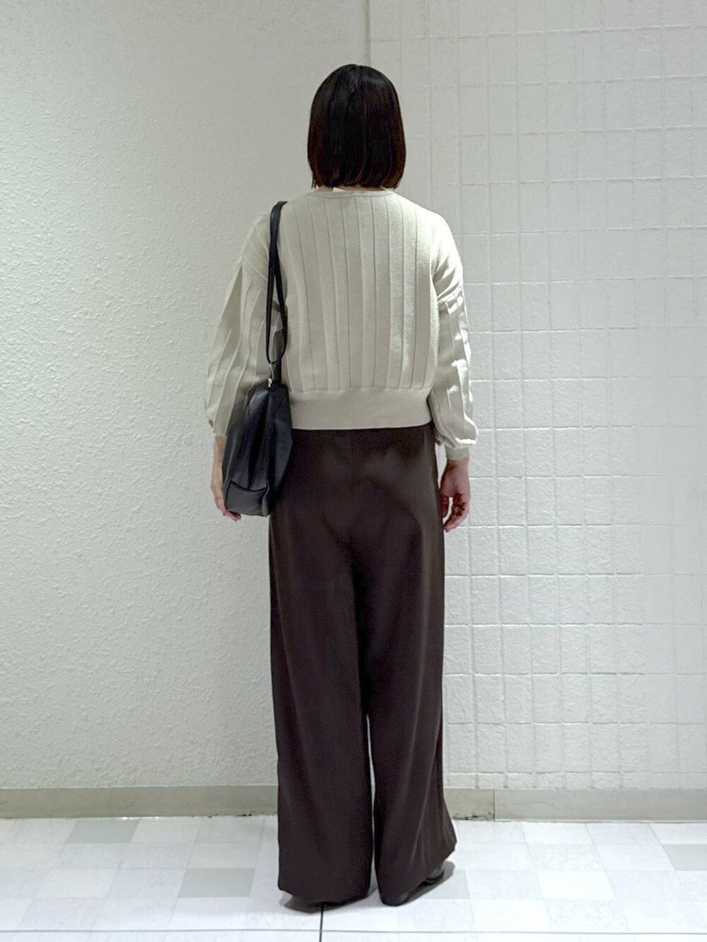 ブラック系のハンドバッグ、ベージュ系のカーディガン/ボレロ、ブラック系のブーツを着用したレディースの秋コーディネートの4枚目の写真