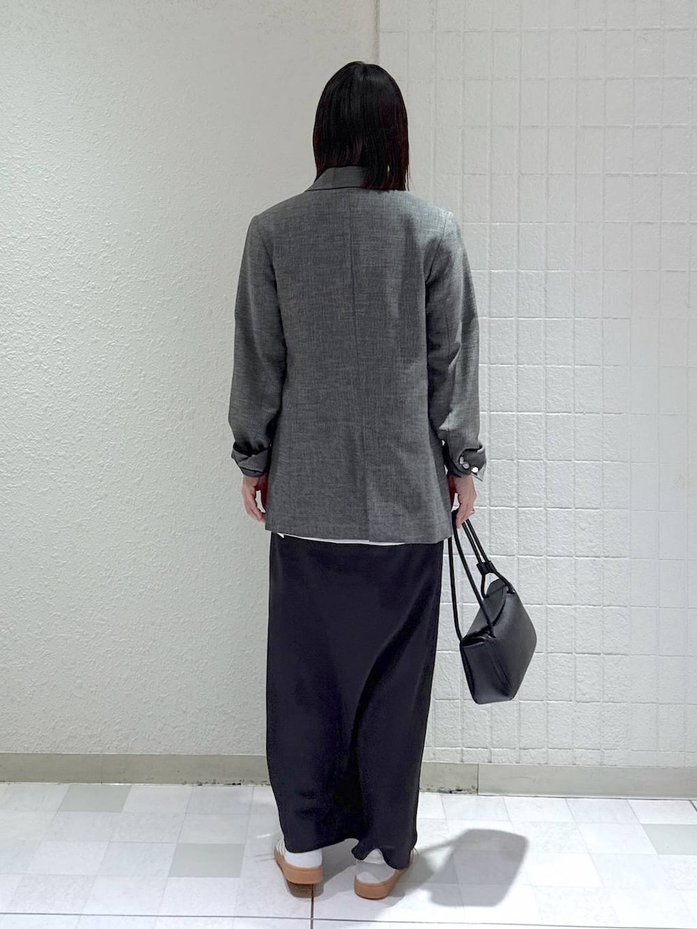 シルバー系のスニーカー、ブラック系のテーラードジャケット、ブラック系のショルダーバッグを着用したレディースの冬コーディネートの4枚目の写真