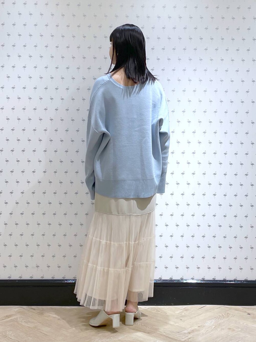 ブルー系のニット/セーター、ベージュ系のスカート、ホワイト系のサンダルを着用したレディースの春コーディネートの2枚目の写真