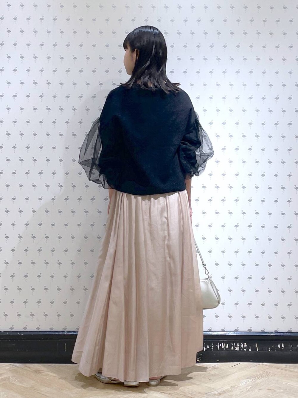 シルバー系のショルダーバッグ、ベージュ系のスカート、シルバー系のパンプスを着用したレディースの冬コーディネートの4枚目の写真
