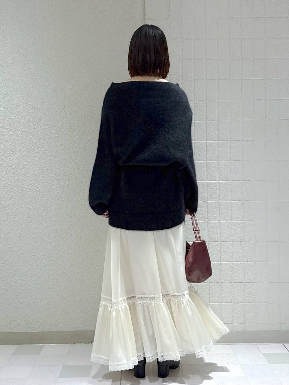 ブラック系のブーツ、ブラック系のワンピース、ホワイト系のスカートを着用したレディースの秋コーディネートの3枚目の写真