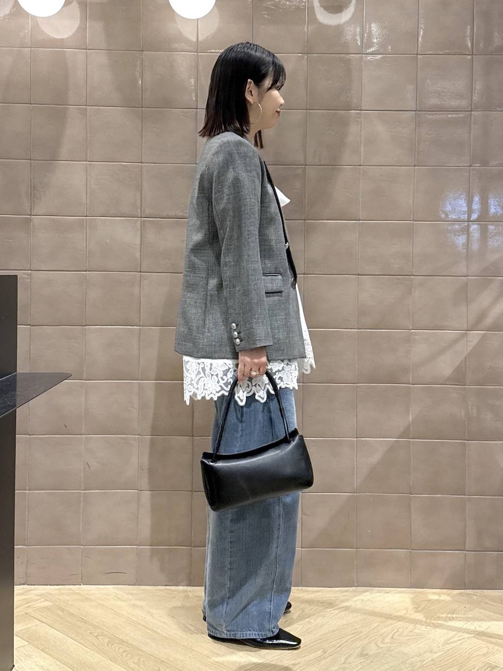 ブルー系のデニムパンツ、ブラック系のテーラードジャケット、ホワイト系のキャミソールを着用したレディースの春コーディネートの2枚目の写真