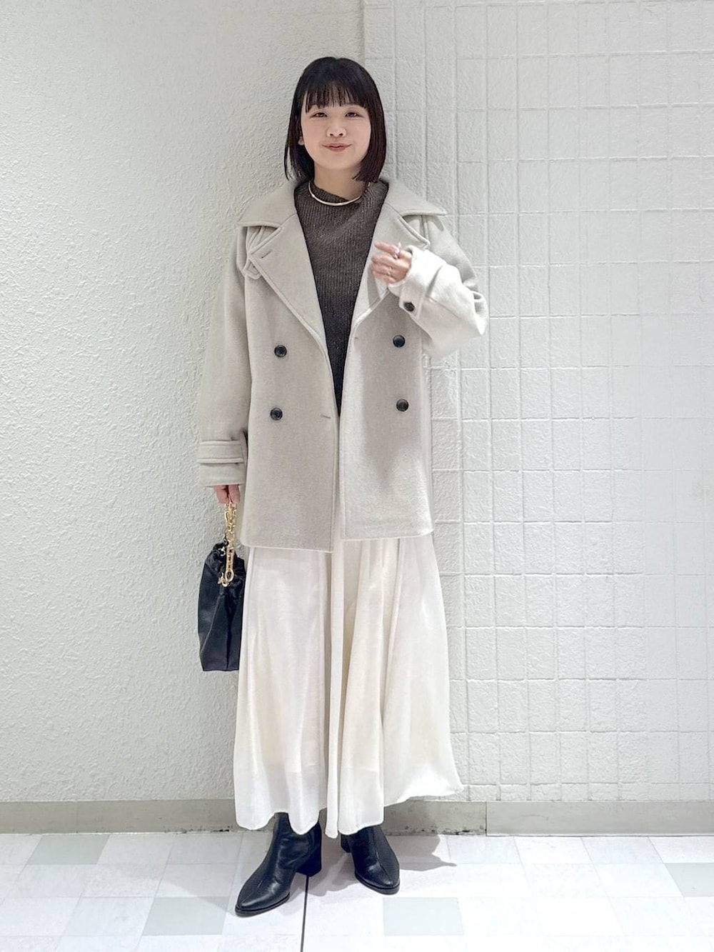 ベージュ系のピーコート、ブラック系のブーツ、ブラウン系のニット/セーターを着用したレディースの冬コーディネートの2枚目の写真