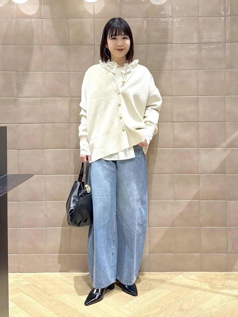 ブルー系のデニムパンツ、ホワイト系のカーディガン/ボレロ、ブラック系のショルダーバッグを着用したレディースの冬コーディネートの5枚目の写真