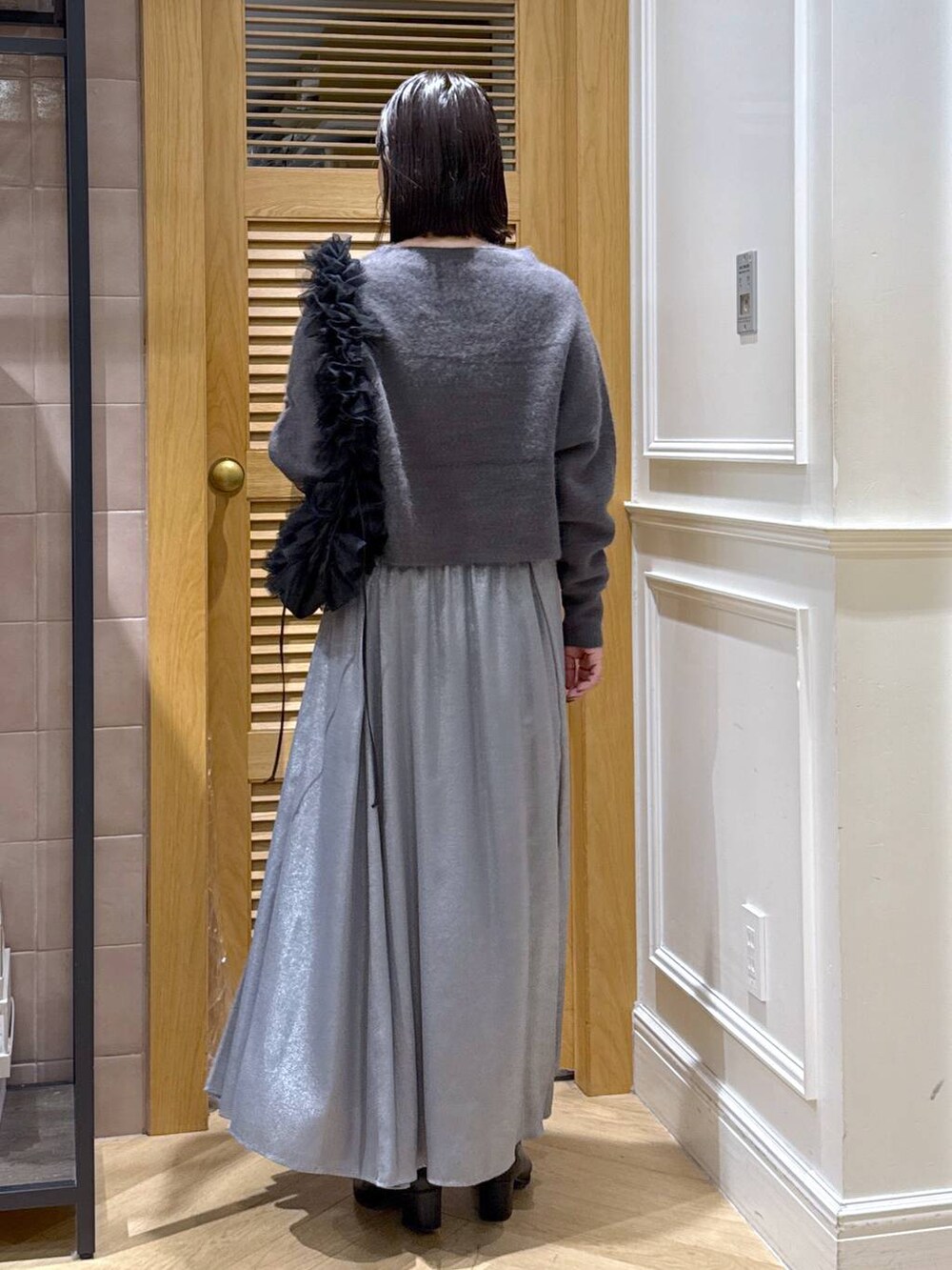 グレー系のニット/セーター、グレー系のスカート、ブラック系のショルダーバッグを着用したレディースの秋コーディネートの5枚目の写真