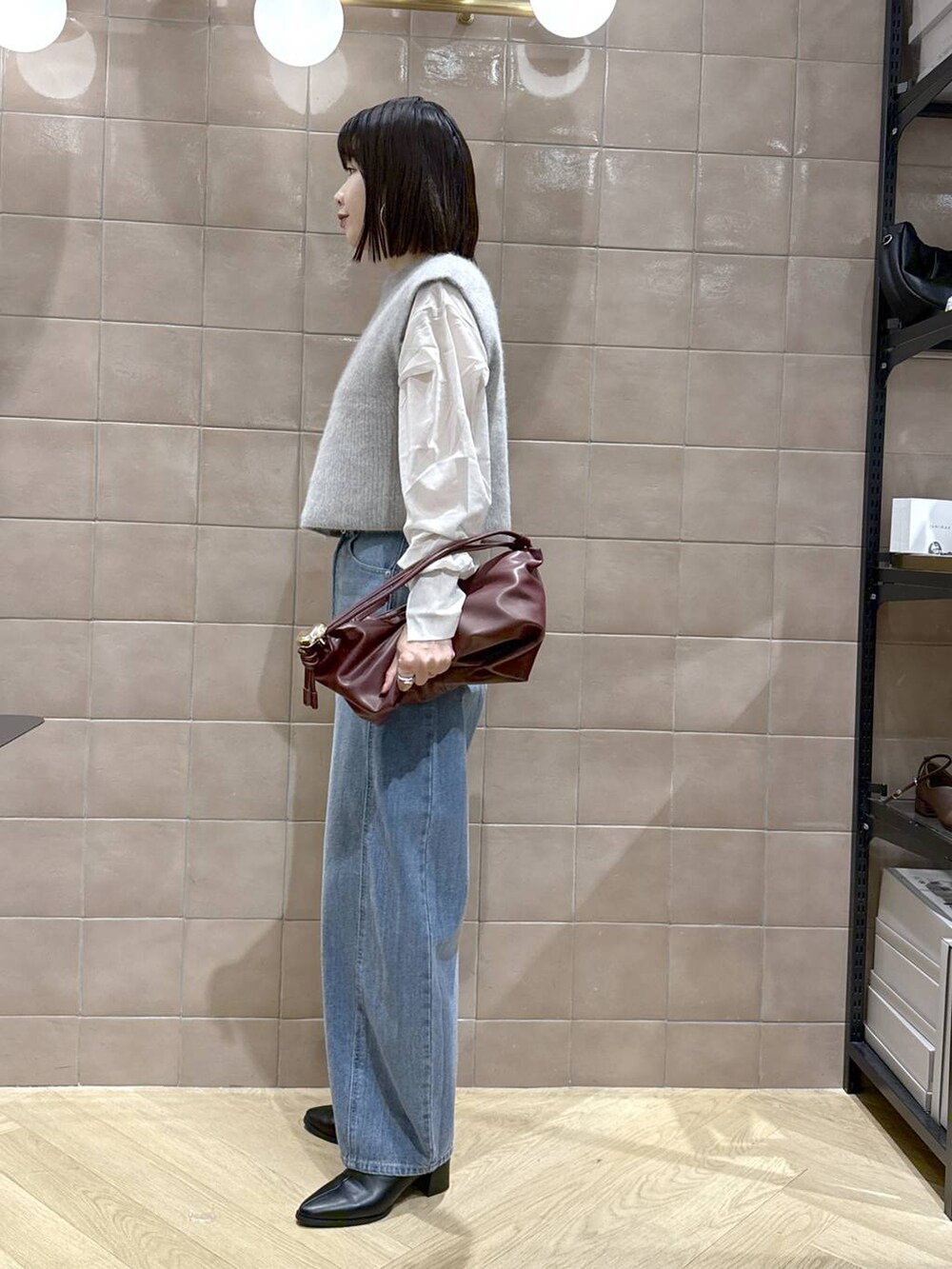 ブルー系のデニムパンツ、ホワイト系のシャツ/ブラウス、ブラック系のブーツを着用したレディースの秋コーディネートの5枚目の写真