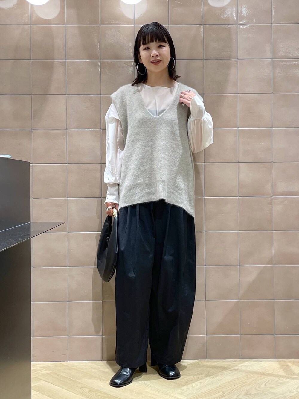 ブラック系のハンドバッグ、ベージュ系のベスト、ベージュ系のシャツ/ブラウスを着用したレディースの秋コーディネートの3枚目の写真