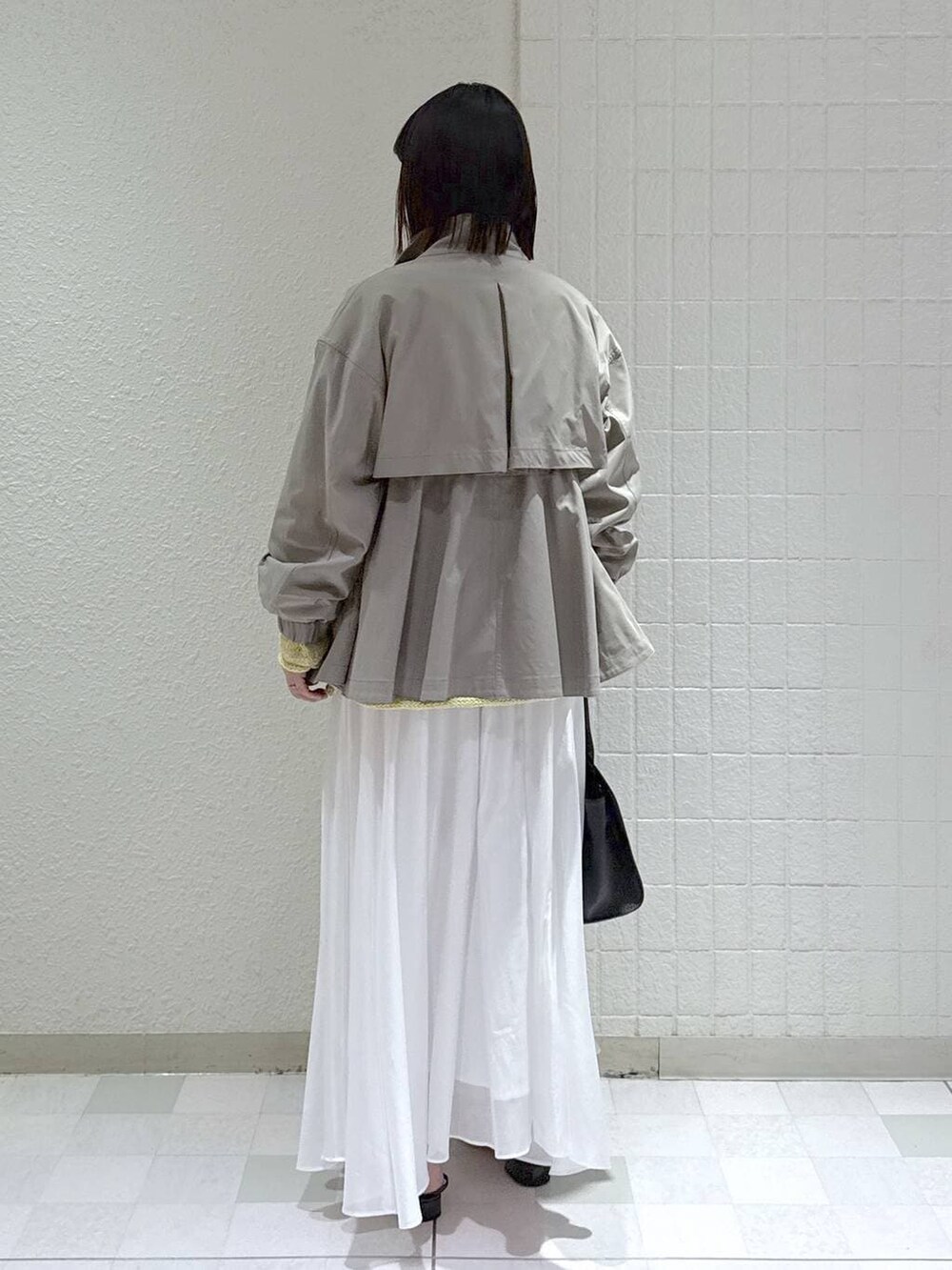 グレー系のブルゾン、ホワイト系のスカート、ブラック系のショルダーバッグを着用したレディースの春コーディネートの3枚目の写真