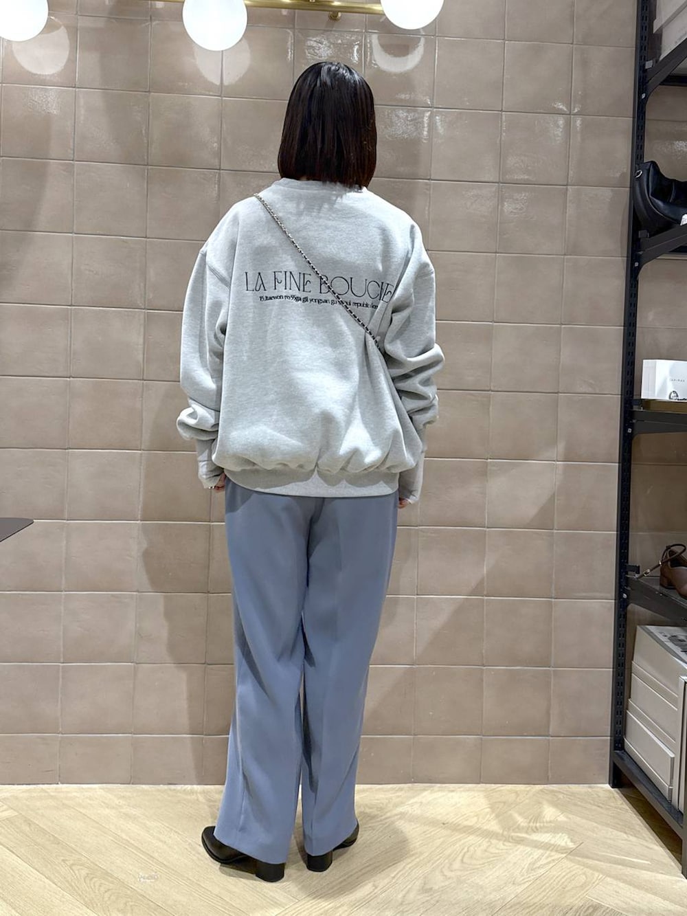 グレー系のTシャツ/カットソー、ブラック系のブーツ、ブルー系のスラックスを着用したレディースの秋コーディネートの4枚目の写真