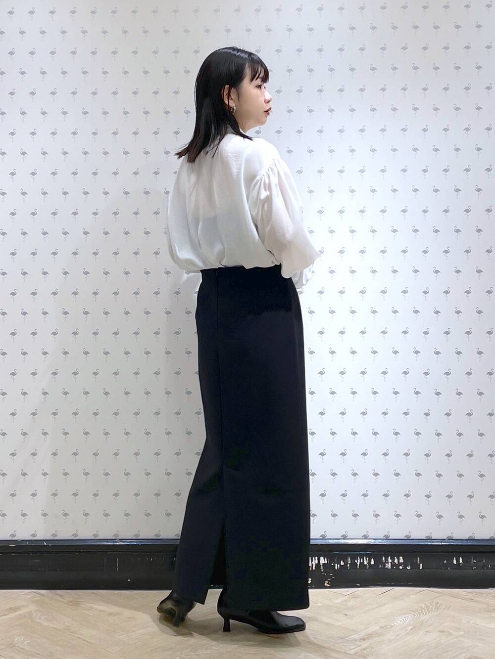 ブラック系のショルダーバッグ、ブラック系のブーツ、ブラック系のスカートを着用したレディースの冬コーディネートの6枚目の写真