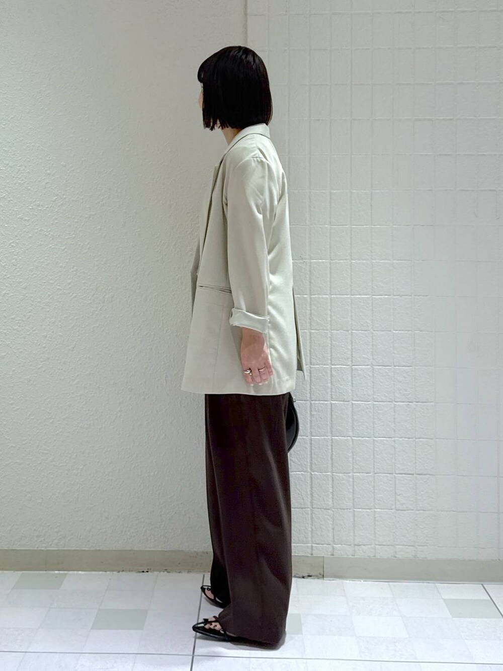 ブラック系のハンドバッグ、ブラック系のサンダル、ベージュ系のテーラードジャケットを着用したレディースの春コーディネートの5枚目の写真