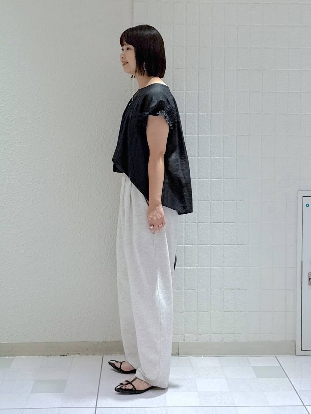 ブラック系のハンドバッグ、ブラック系のサンダル、グレー系のスウェットパンツを着用したレディースの夏コーディネートの5枚目の写真