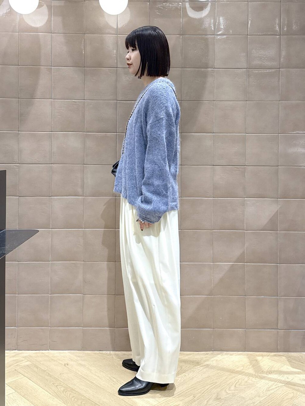 ホワイト系のスラックス、グレー系のTシャツ/カットソー、ブラック系のブーツを着用したレディースの秋コーディネートの4枚目の写真