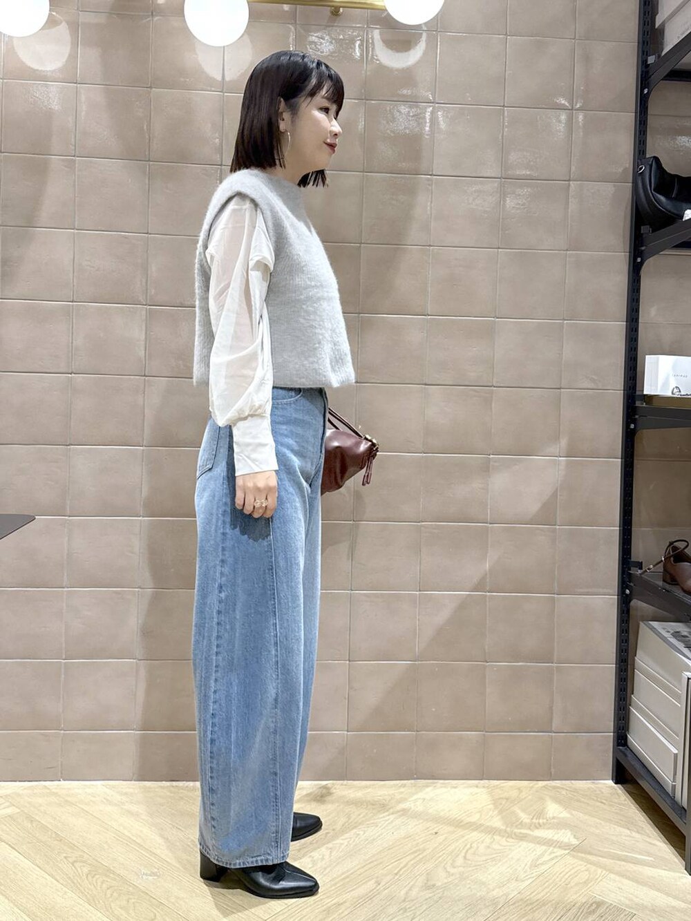 ブルー系のデニムパンツ、ホワイト系のシャツ/ブラウス、ブラック系のブーツを着用したレディースの秋コーディネートの3枚目の写真