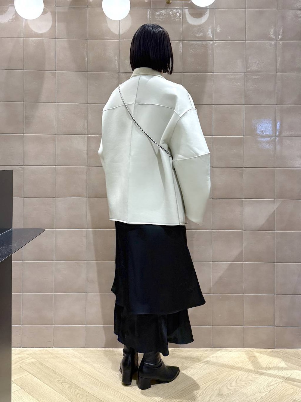 ブラック系のブーツ、ベージュ系のブルゾン、ブルー系のショルダーバッグを着用したレディースの秋コーディネートの2枚目の写真