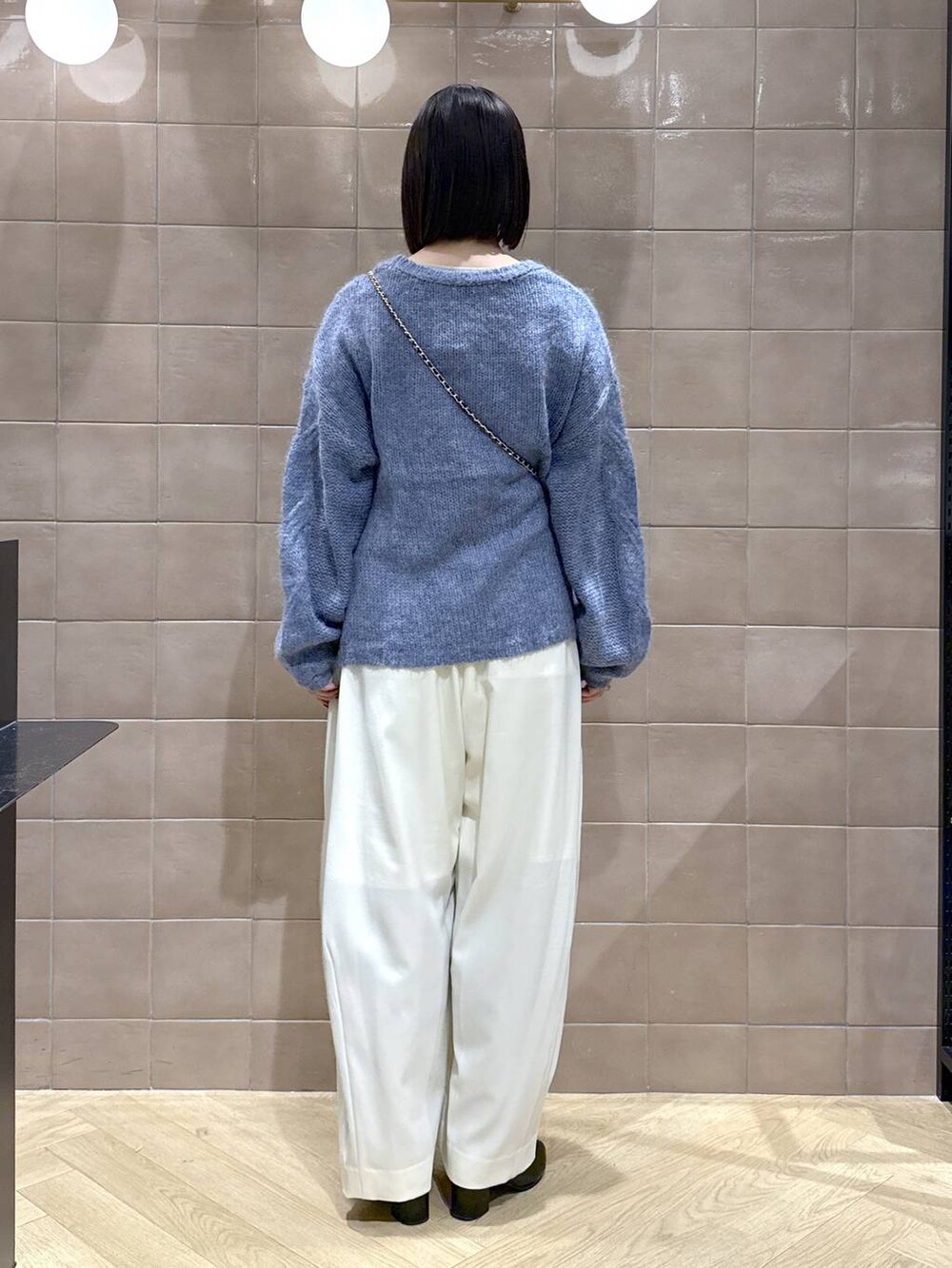 ホワイト系のスラックス、グレー系のTシャツ/カットソー、ブラック系のブーツを着用したレディースの秋コーディネートの3枚目の写真