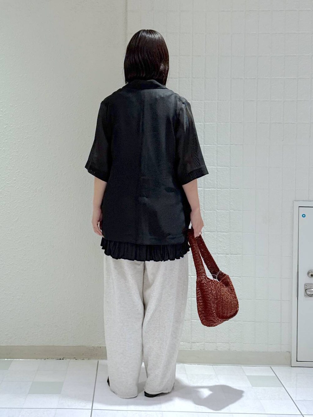 ブラック系のサンダル、ブラウン系のハンドバッグ、グレー系のスウェットパンツを着用したレディースの夏コーディネートの3枚目の写真