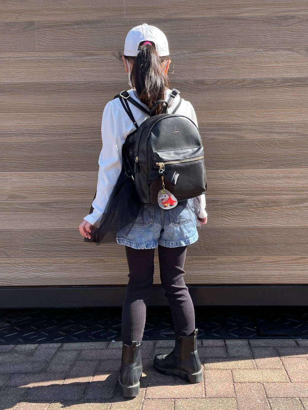 ブラック系のブーツ、ブラック系のTシャツ/カットソー、ブラック系のバックパック/リュックを着用したキッズの冬コーディネートの2枚目の写真