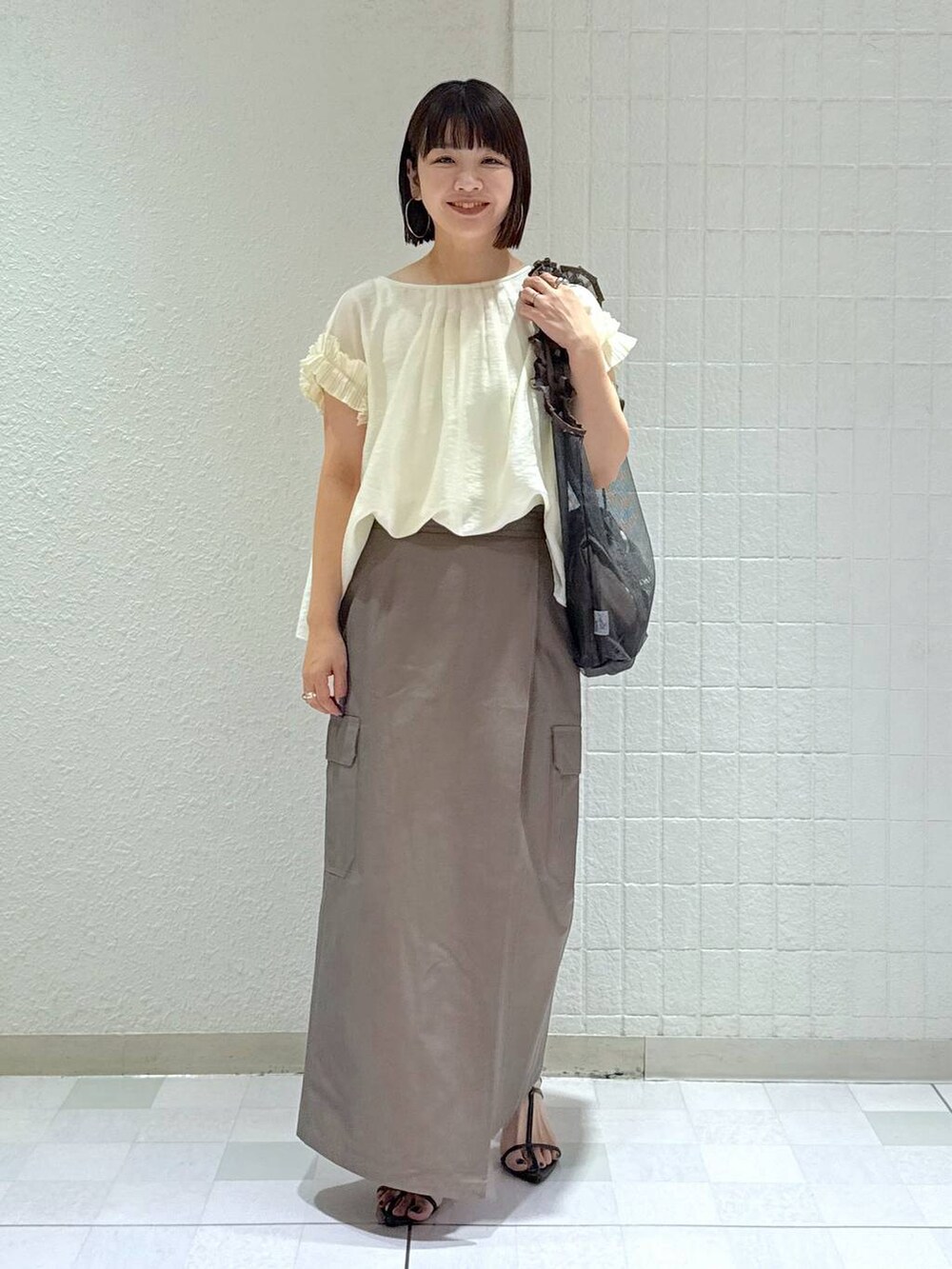 ブラック系のサンダル、ブラック系のトートバッグ、グリーン系のスカートを着用したレディースの夏コーディネートの2枚目の写真