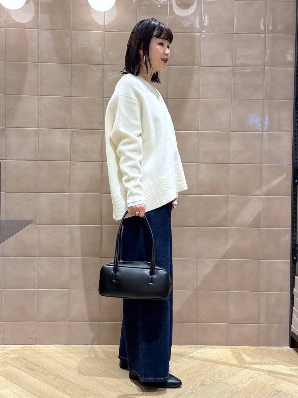 ホワイト系のニット/セーター、グレー系のTシャツ/カットソー、ブラック系のブーツを着用したレディースの冬コーディネートの3枚目の写真