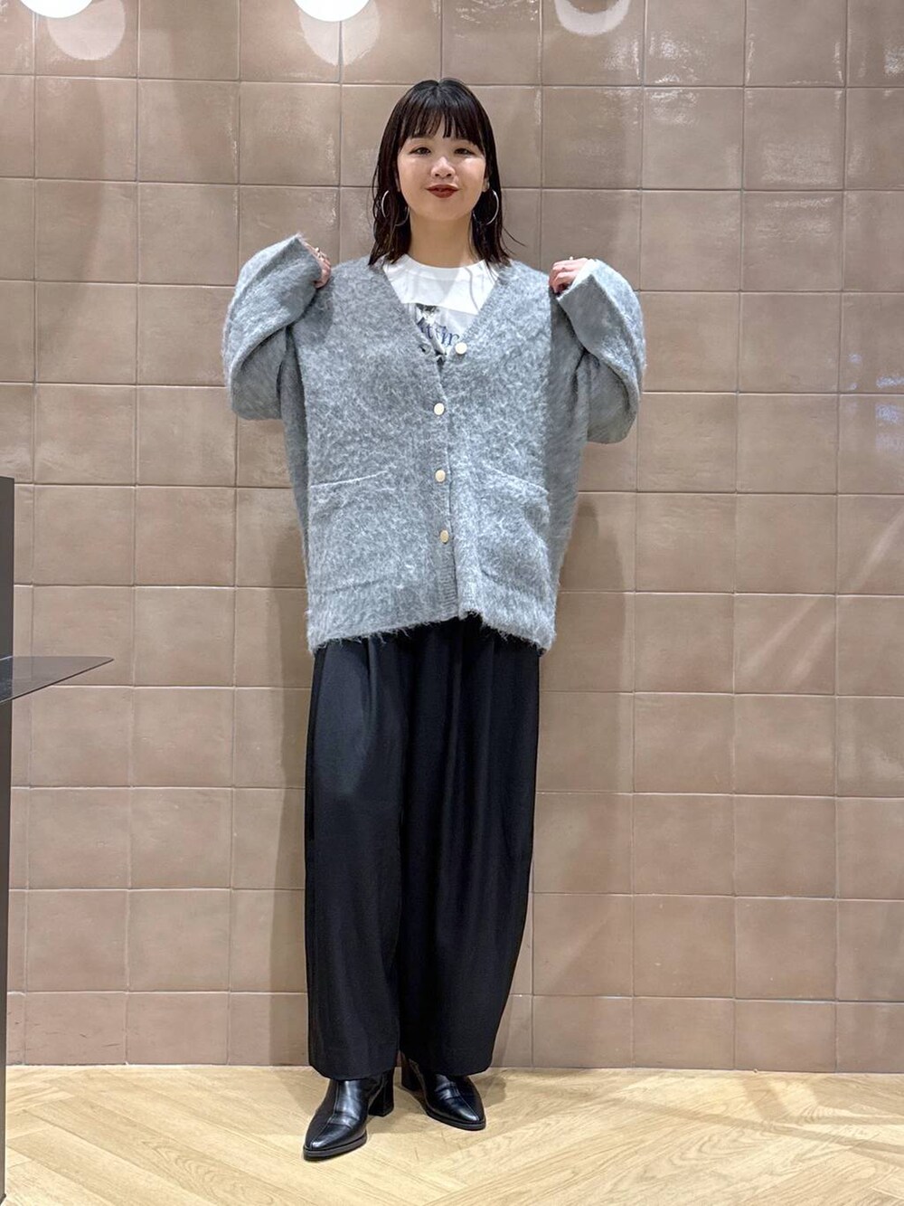 ブラック系のスラックス、グレー系のカーディガン/ボレロ、ホワイト系のTシャツ/カットソーを着用したレディースの冬コーディネートの3枚目の写真