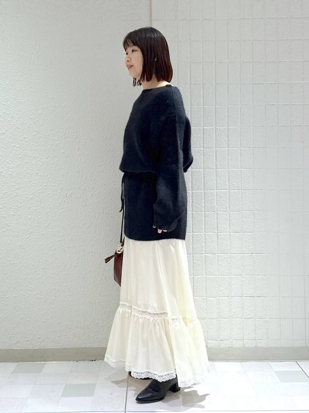 ブラック系のブーツ、ブラック系のワンピース、ホワイト系のスカートを着用したレディースの秋コーディネートの4枚目の写真