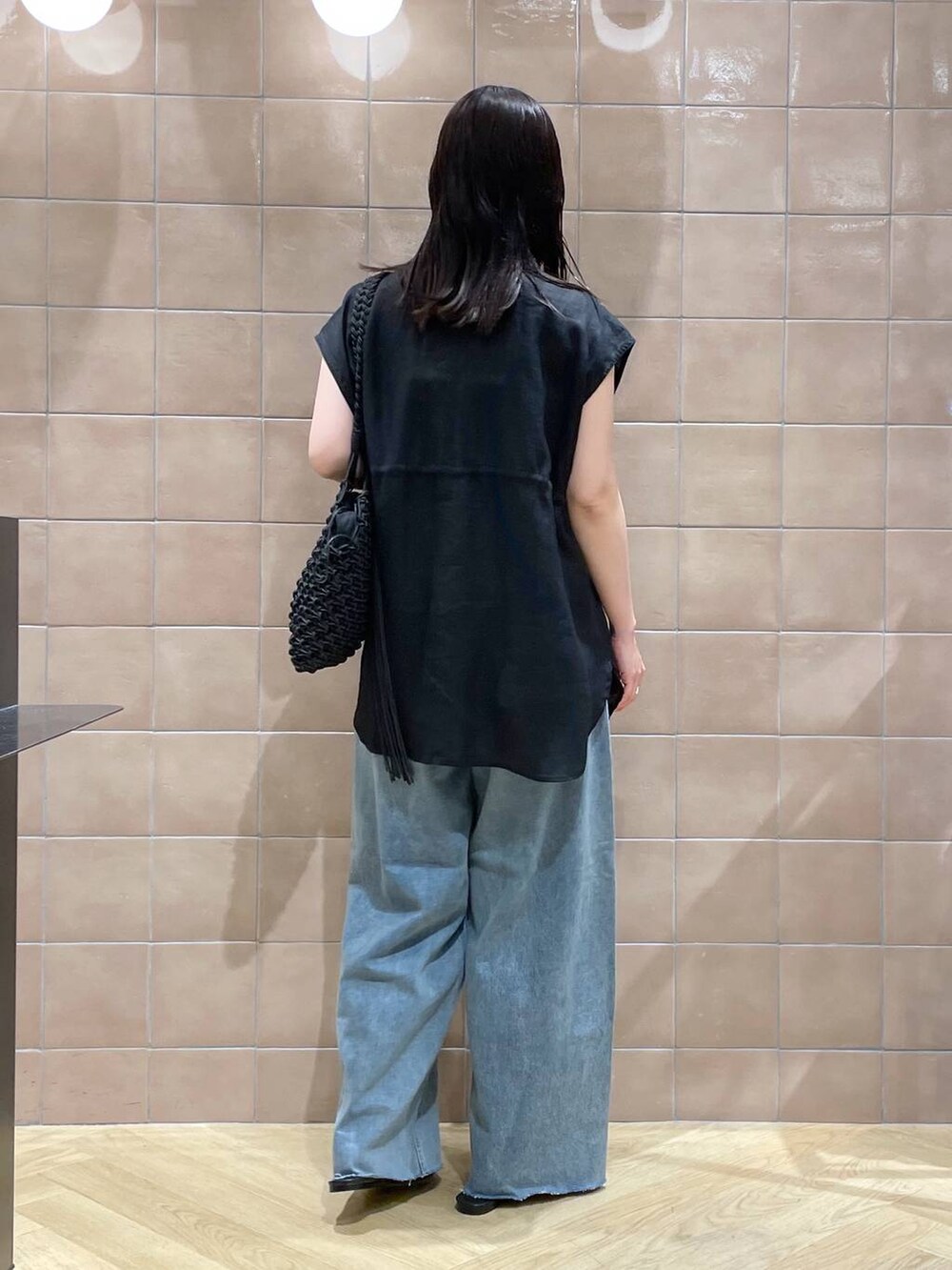 ブラック系のショルダーバッグ、ブラック系のベスト、ブラック系のサンダルを着用したレディースの春コーディネートの2枚目の写真