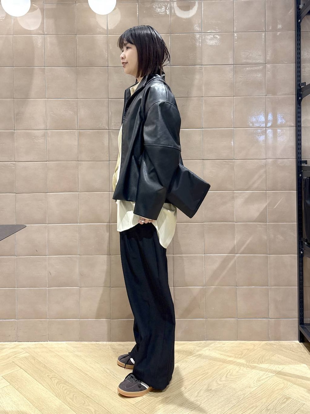 ブラック系のスラックス、ブラック系のブルゾン、イエロー系のシャツ/ブラウスを着用したレディースの冬コーディネートの5枚目の写真