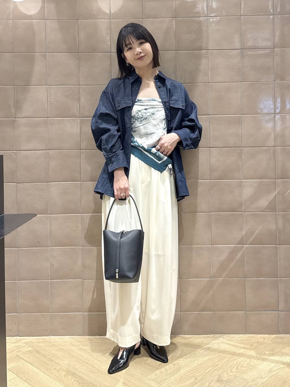 ホワイト系のスラックス、ブラック系のパンプス、ブラック系のショルダーバッグを着用したレディースの春コーディネートの2枚目の写真