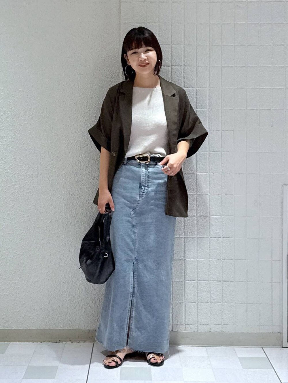 ブラック系のハンドバッグ、ブラック系のサンダル、ブルー系のデニムスカートを着用したレディースの秋コーディネートの5枚目の写真