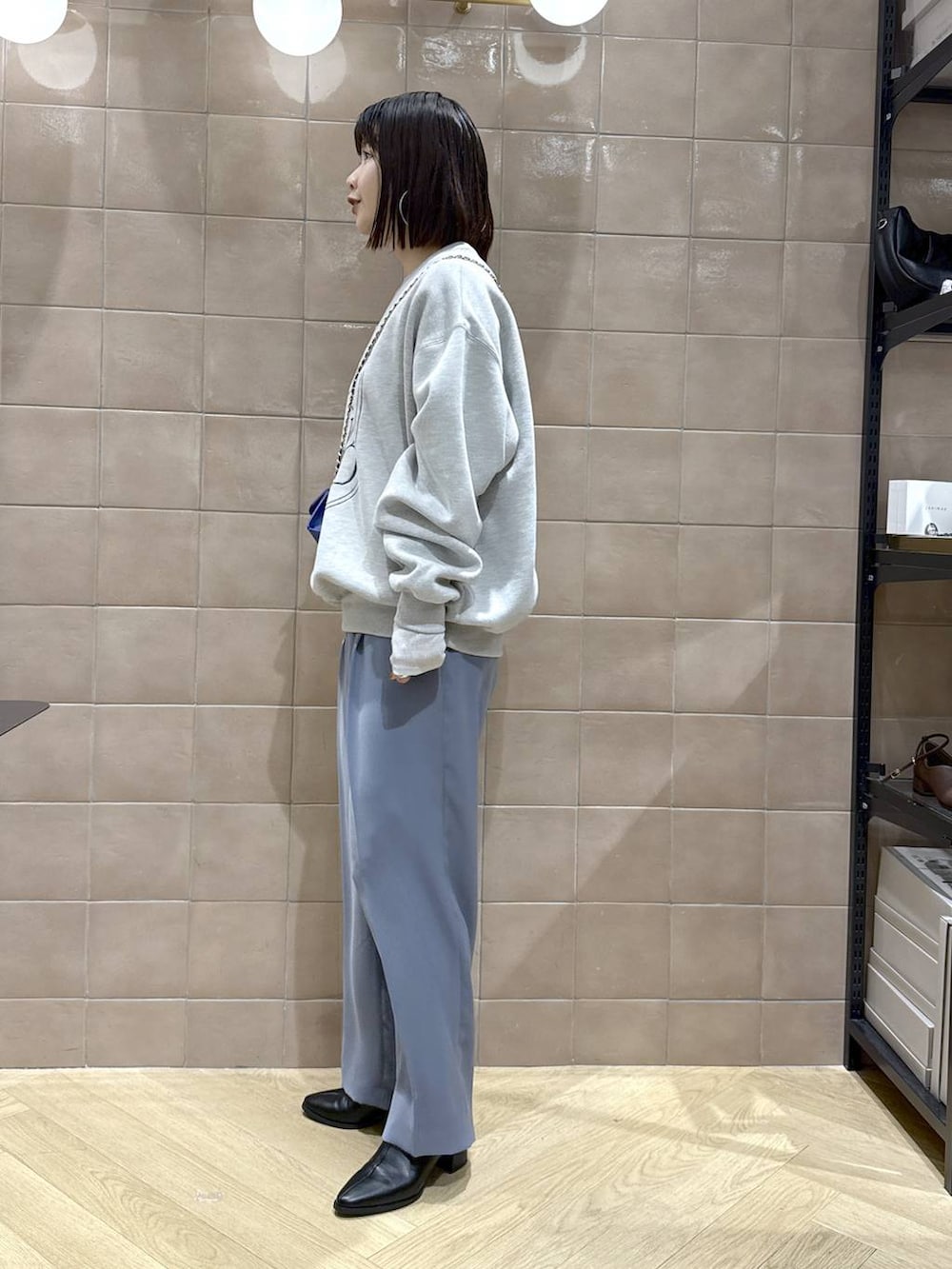 グレー系のTシャツ/カットソー、ブラック系のブーツ、ブルー系のスラックスを着用したレディースの秋コーディネートの5枚目の写真