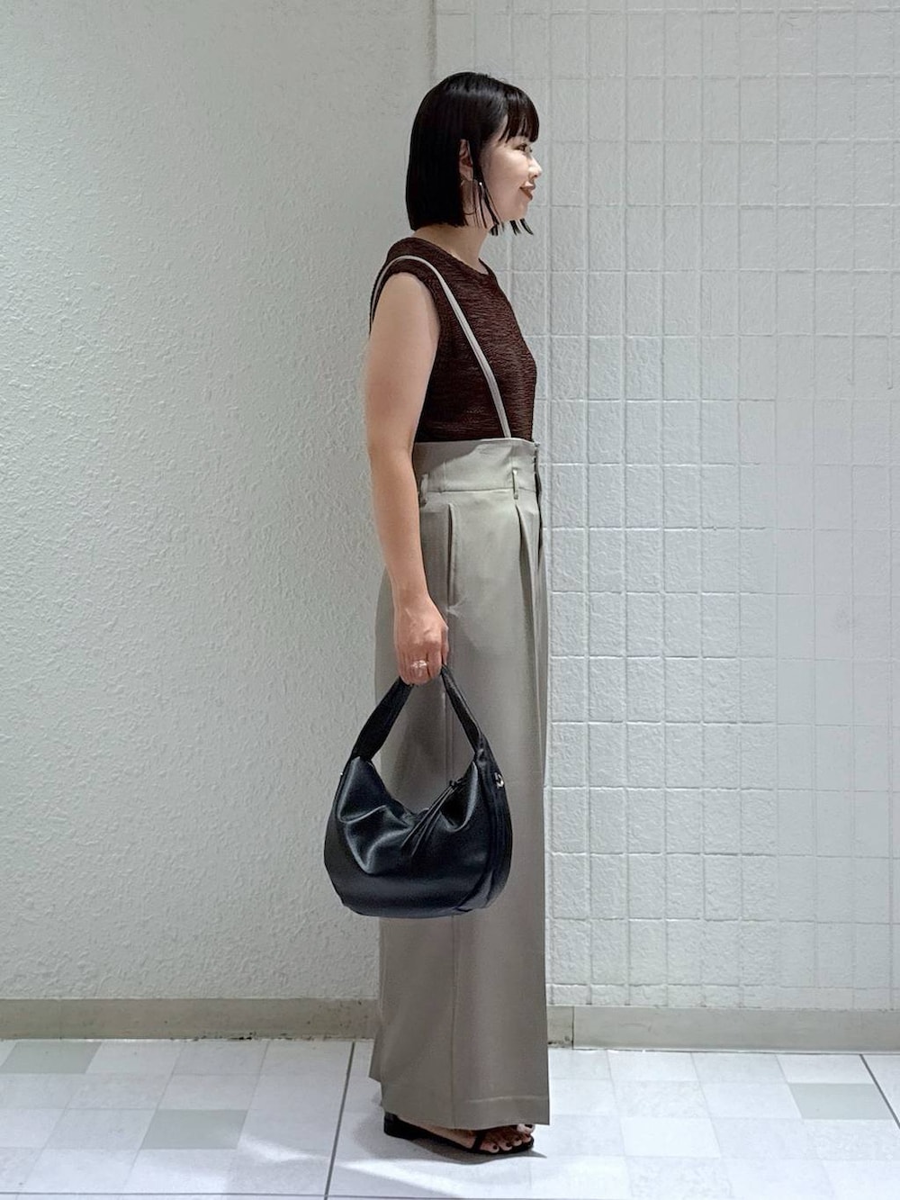 ブラック系のハンドバッグ、ブラック系のサンダル、グレー系のその他パンツを着用したレディースの夏コーディネートの2枚目の写真