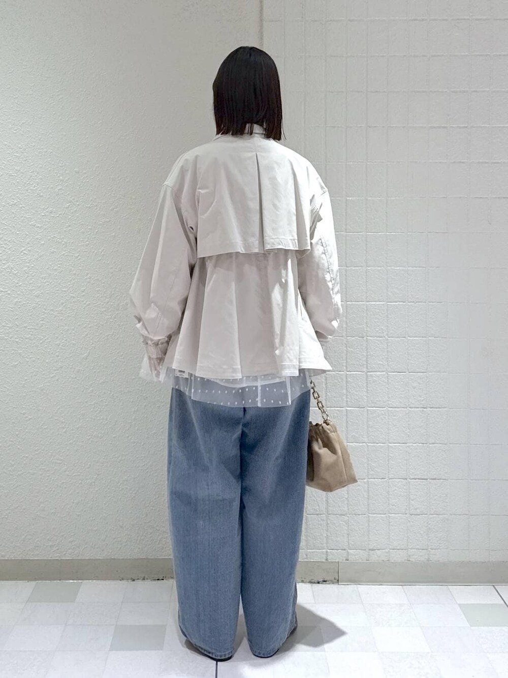 ブルー系のデニムパンツ、ベージュ系のブルゾン、ベージュ系のショルダーバッグを着用したレディースの春コーディネートの3枚目の写真