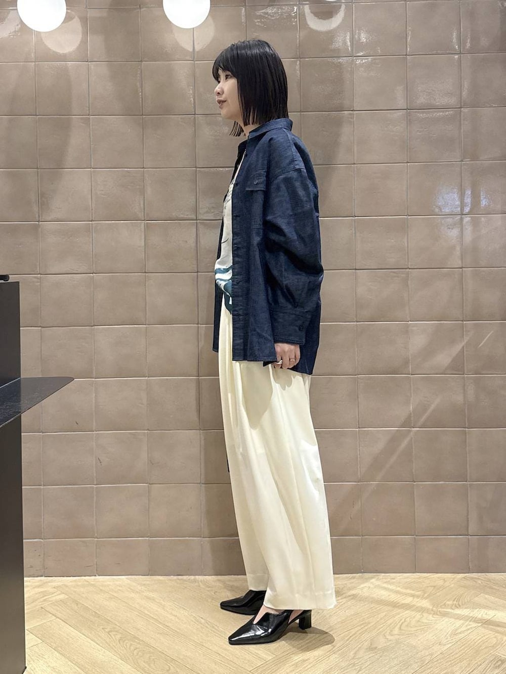 ホワイト系のスラックス、ブラック系のパンプス、ブラック系のショルダーバッグを着用したレディースの春コーディネートの6枚目の写真