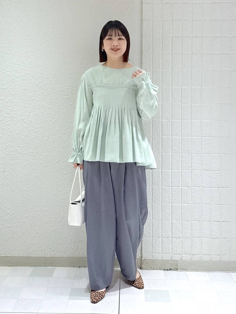 グレー系のスラックス、グリーン系のシャツ/ブラウス、ホワイト系のショルダーバッグを着用したレディースの冬コーディネートの2枚目の写真