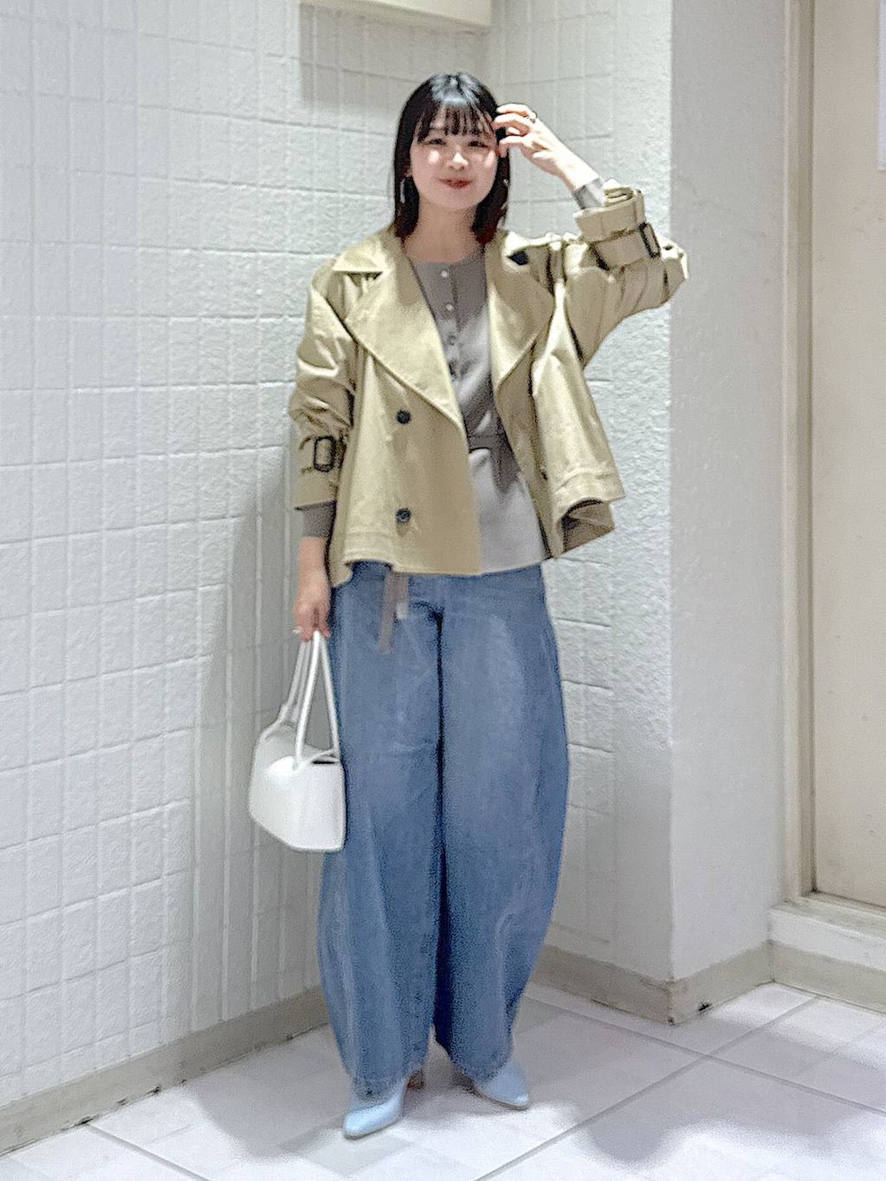 ブルー系のデニムパンツ、グレー系のカーディガン/ボレロ、ベージュ系のトレンチコートを着用したレディースの冬コーディネートの2枚目の写真