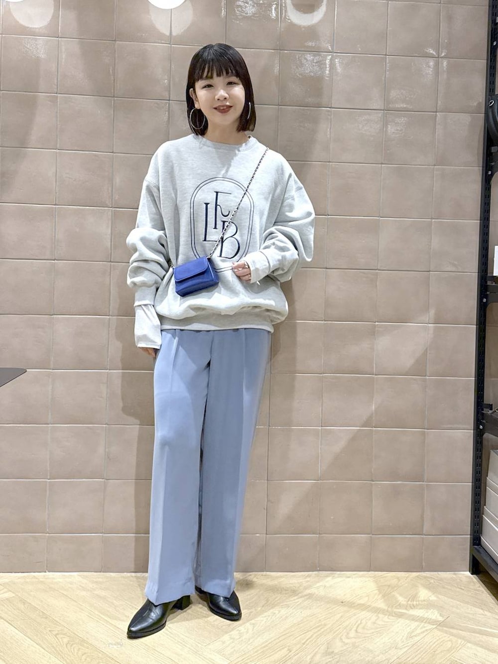 グレー系のTシャツ/カットソー、ブラック系のブーツ、ブルー系のスラックスを着用したレディースの秋コーディネートの2枚目の写真