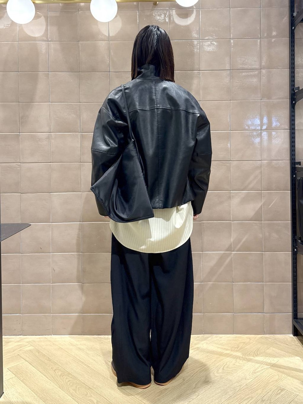 ブラック系のスラックス、ブラック系のブルゾン、イエロー系のシャツ/ブラウスを着用したレディースの冬コーディネートの4枚目の写真